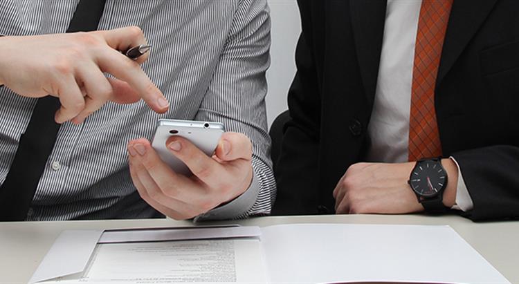 Work colleagues pointing to phone discussion 